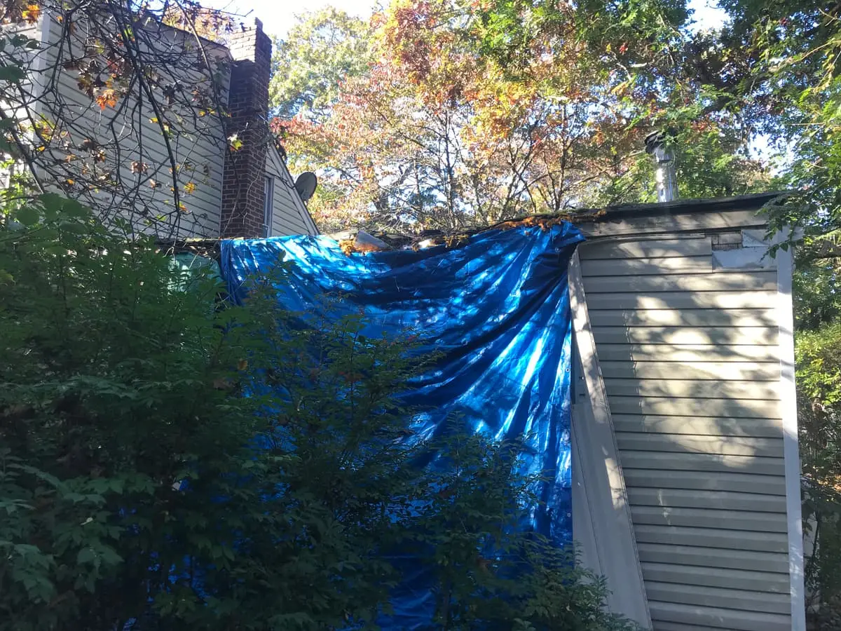 Selling a rental property in Medford: blue tarp hung over the back of a house