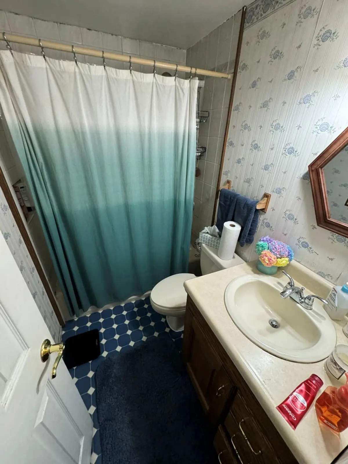Selling a house with a reverse mortgage in Medford: dated bathroom with floral wallpaper and a blue rug