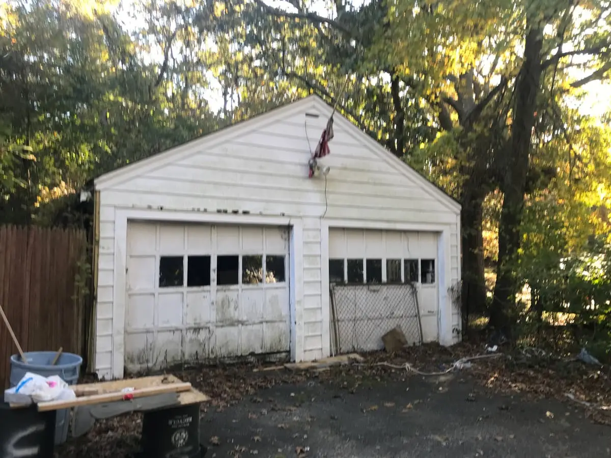 Selling a fire-damaged house in Medford: detached two-car garage with worn doors
