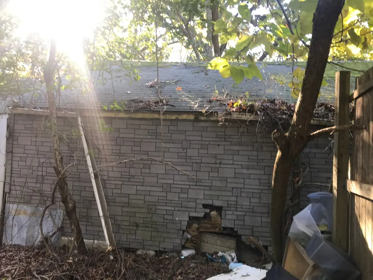 Selling a house as-is in Medford: garage wall with crumbling block and a hole near the base