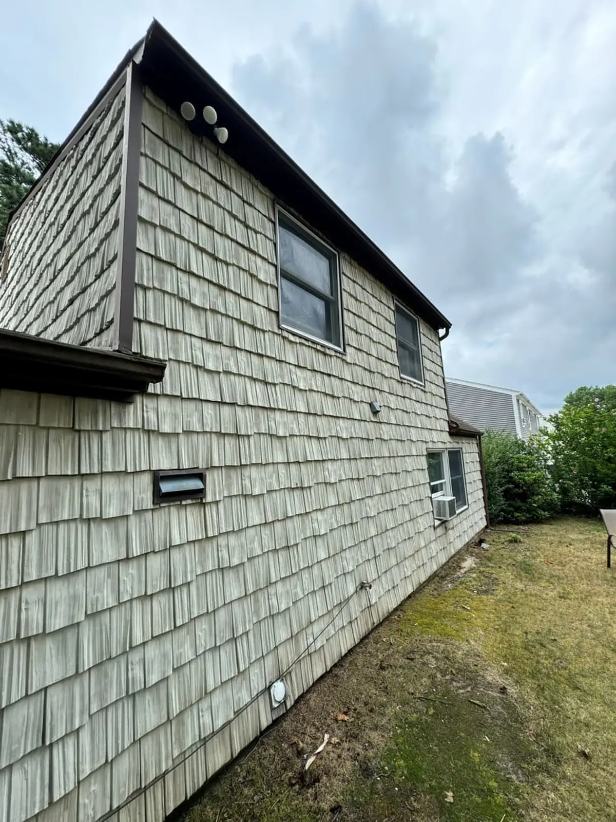 Side of a shingled house under a cloudy sky, Medford, NY